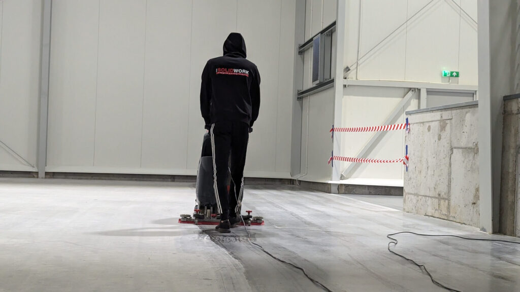 Sprzątanie dużej hali magazynowej – pracownik SolidWork czyści posadzkę maszyną